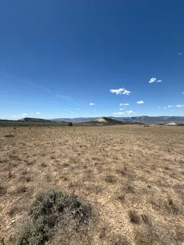 Expansive open landscape with distant hills under a clear blue sky