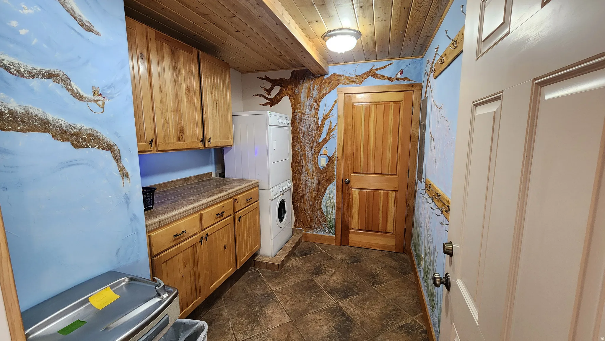 Utility space featuring wood-finish cabinetry, a laminate countertop, and tile flooring