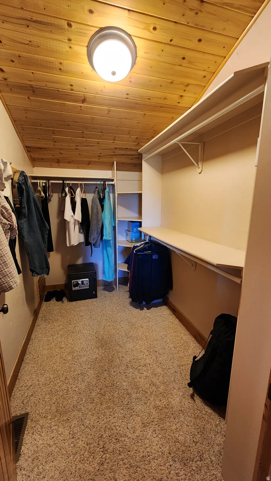 Walk-in closet featuring a wood-plank ceiling, recessed lighting, carpet flooring, and built-in shelving with hanging rods