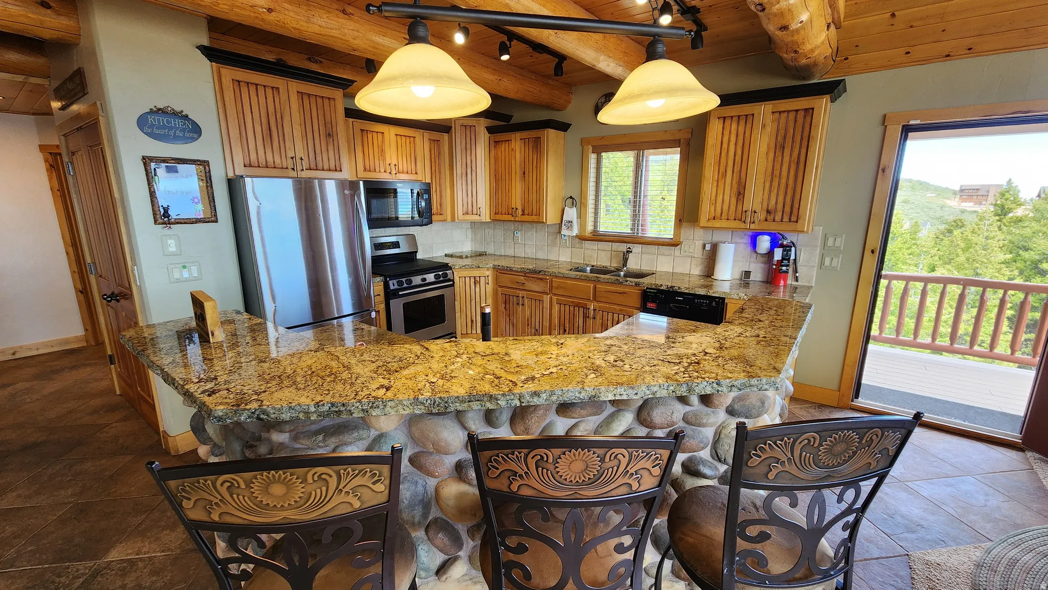 Kitchen featuring a stone-clad island with a granite countertop, wood-finish cabinetry, stainless steel appliances, and wood-finish flooring