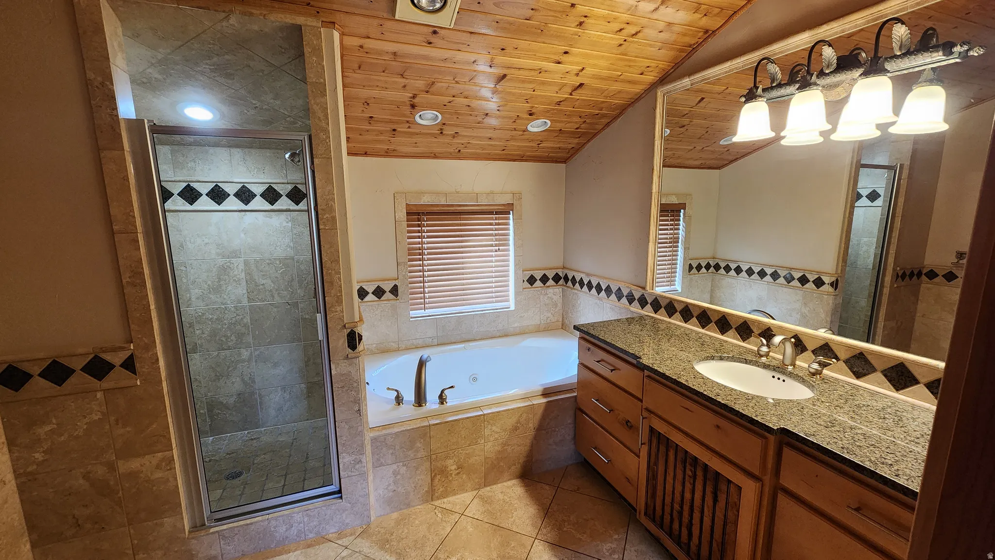 Bathroom featuring a wood-panel ceiling, stone tile flooring, and a jetted soaking tub