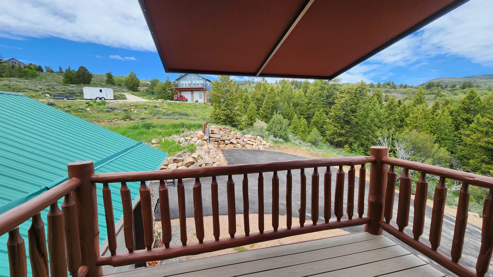 Deck featuring wood-finish railings and flooring, with a retractable awning