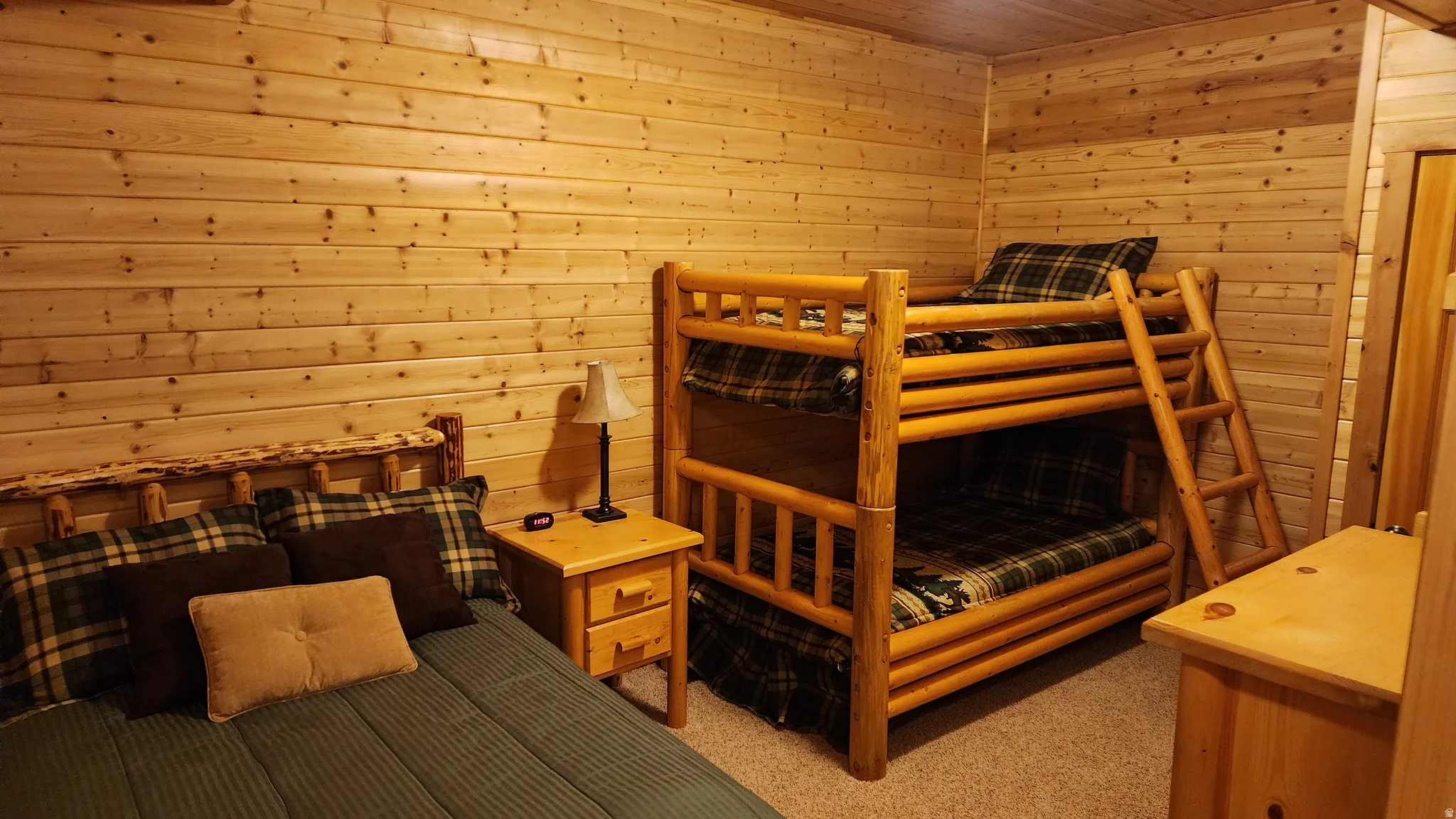 Wood-finish wall paneling, a wood-finish bunk bed frame, a wood-finish single bed frame, a wood-finish nightstand, and a wood-finish dresser