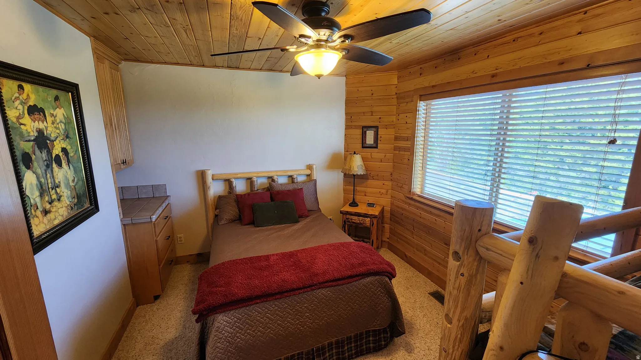 Interior space featuring wood-paneled walls and ceiling, a window with horizontal blinds, and a built-in wood cabinet with a tiled countertop