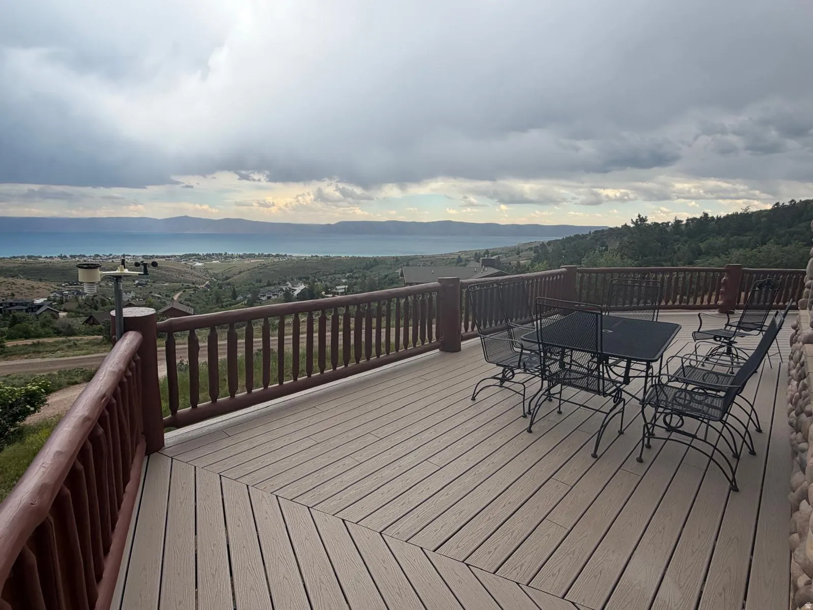 Expansive outdoor deck featuring wood-finish flooring, a sturdy wood railing, and stone siding