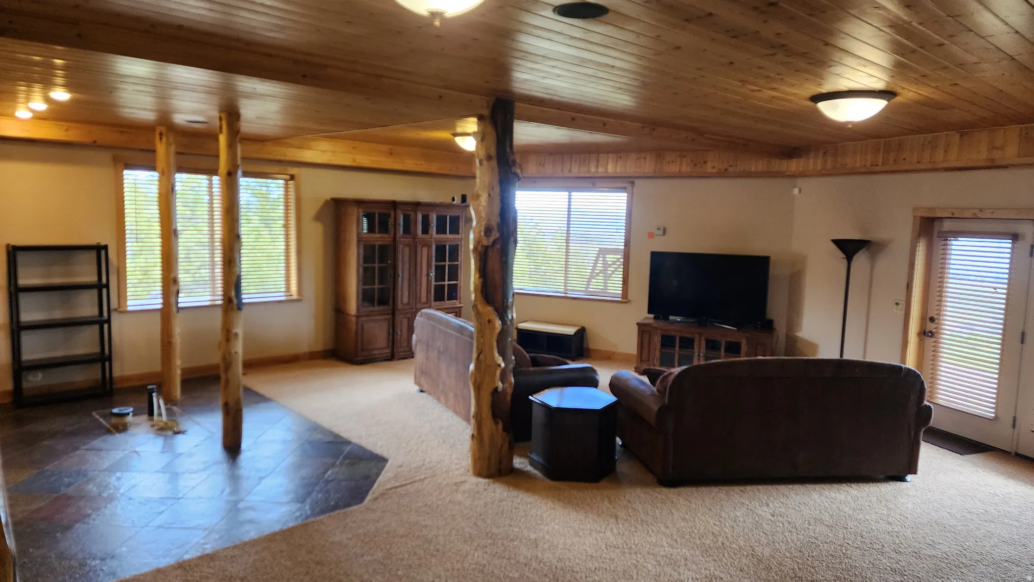 Spacious room featuring wood-paneled ceilings, recessed lighting, and a blend of carpet and tile flooring