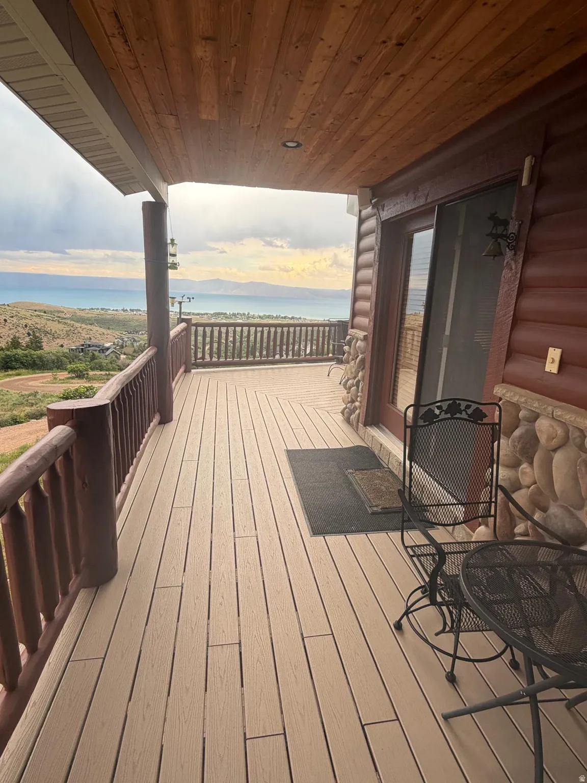 Expansive covered deck featuring composite decking, log railing, and a tongue-and-groove wood ceiling with recessed lighting