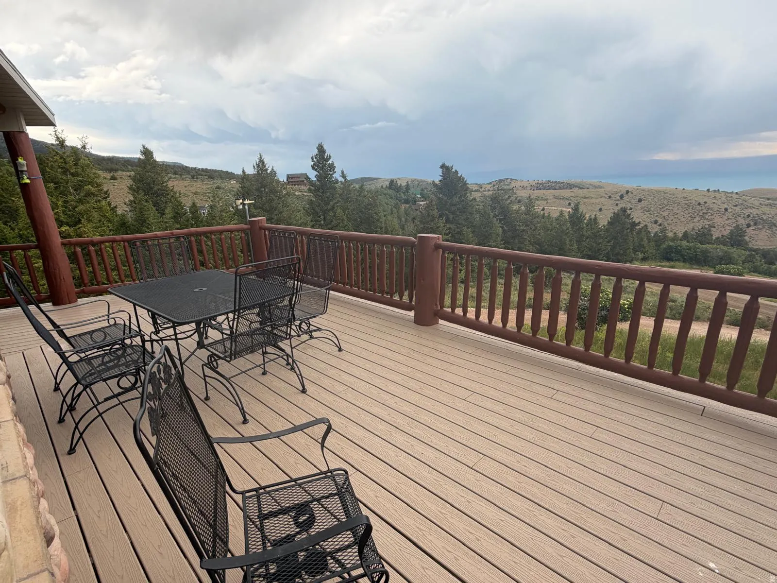 Expansive outdoor deck featuring wood-finish composite decking, a log-style railing, and a stone-clad exterior wall portion