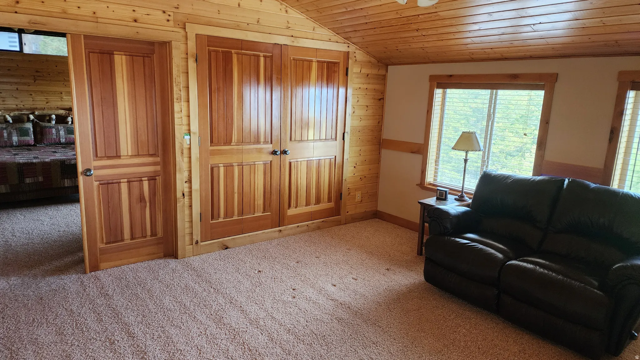 Carpeted room featuring natural wood paneling, wood-finish ceiling, and natural wood doors