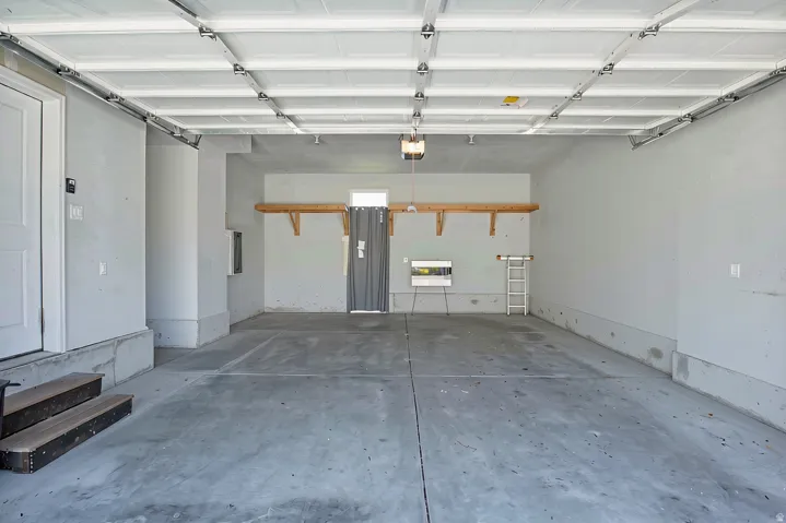 Spacious garage featuring a concrete floor, built-in shelving, and a panel garage door