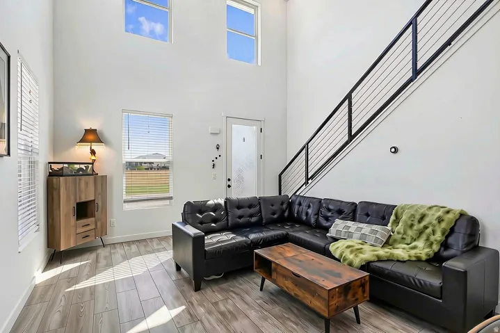 High ceilings with upper windows, wood-finish flooring, and a modern cable railing staircase
