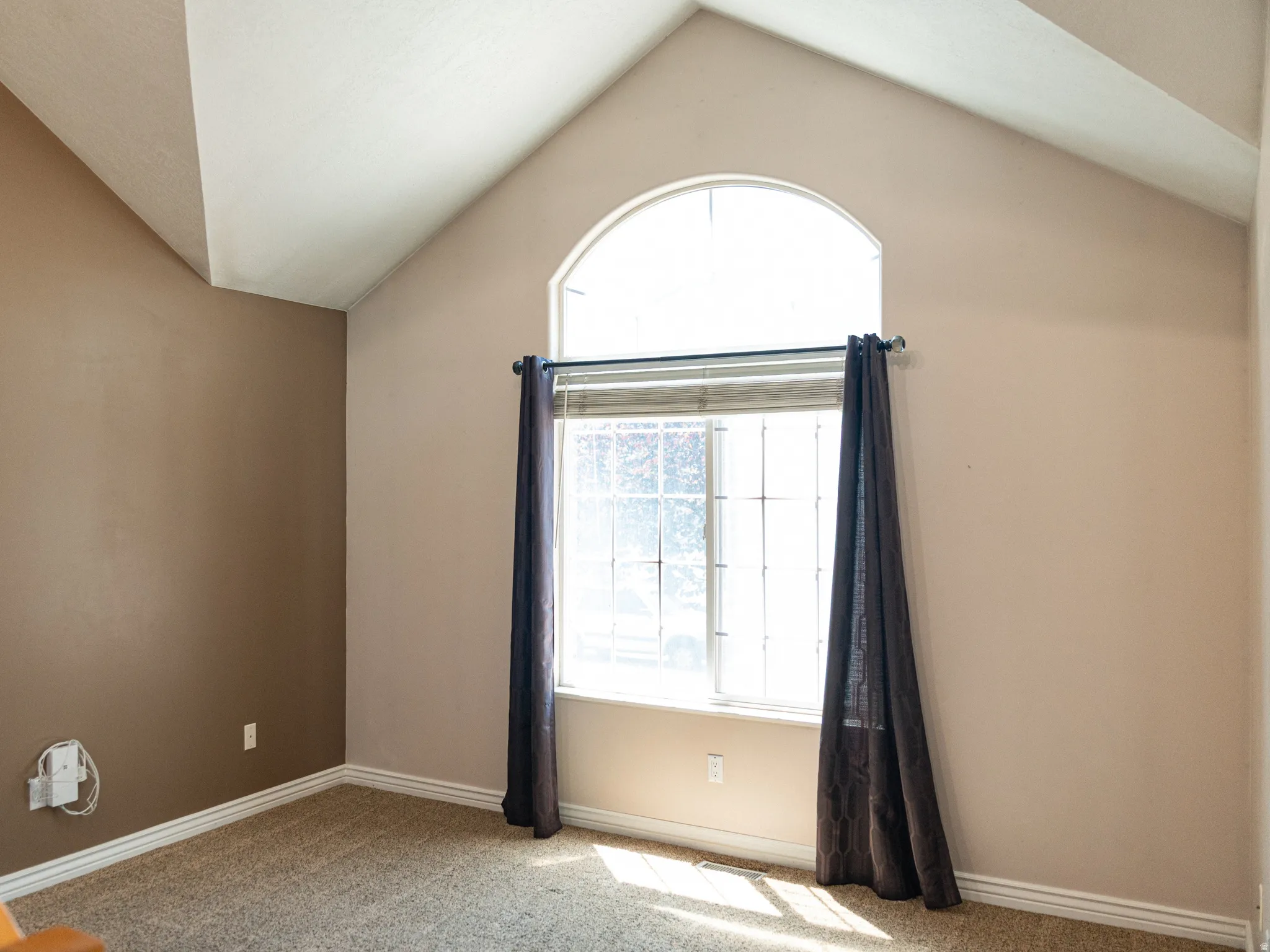Vaulted ceilings featuring a prominent arched window and a lower rectangular window with grid inserts