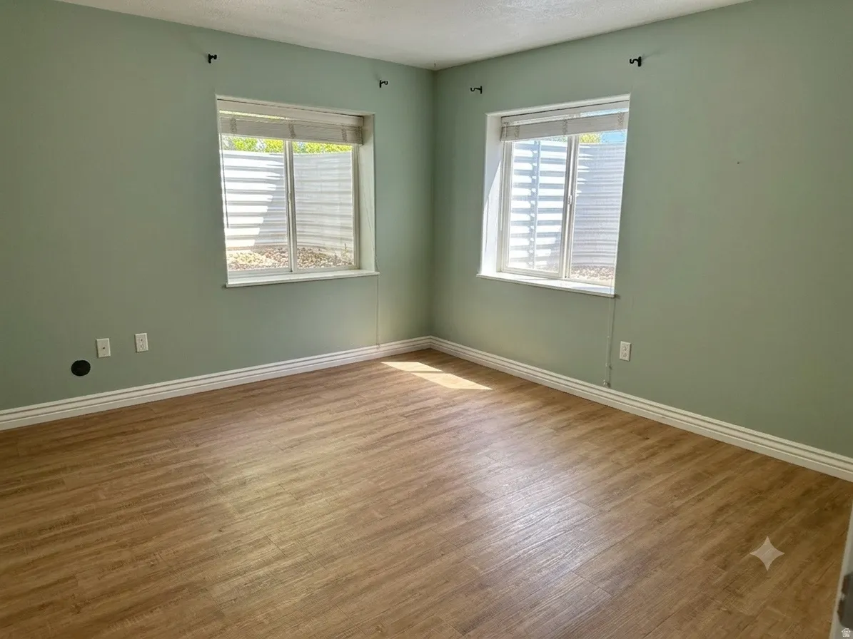 Room featuring light  walls, wood-finish flooring, and white baseboards