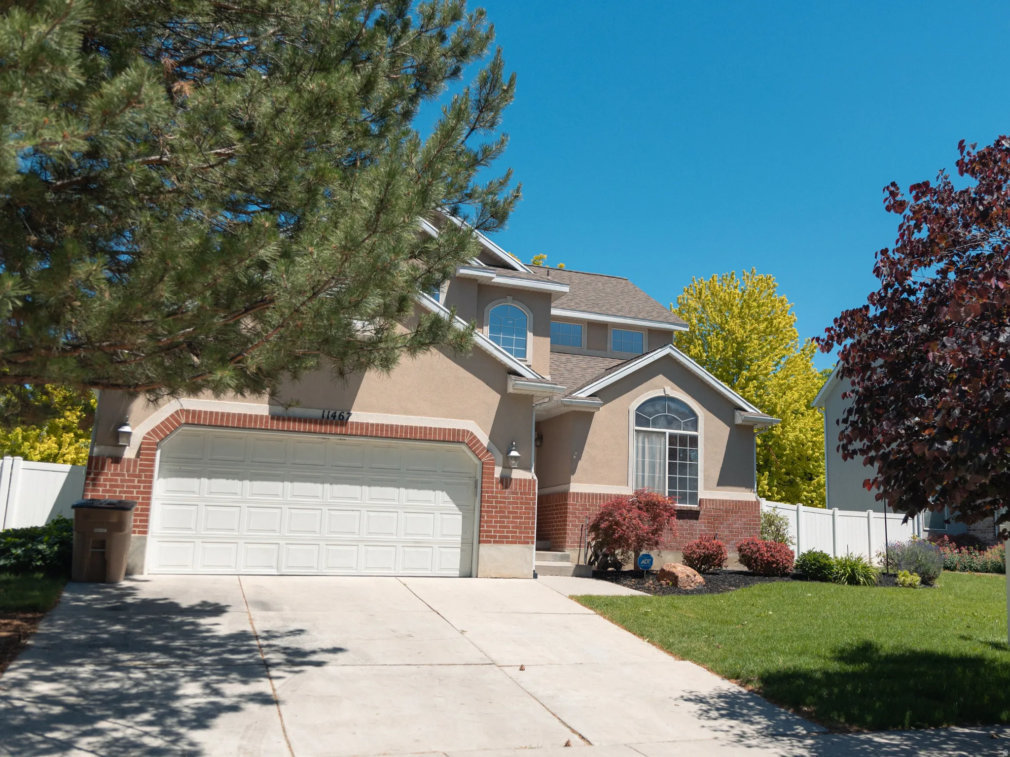 Two-story residence featuring a brick and stucco exterior, an arched window detail, and an attached two-car garage