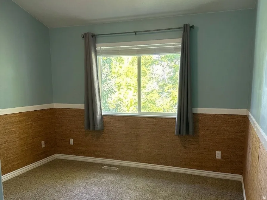 Room featuring carpet flooring, a window with exterior views, and a ceiling fan with integrated lighting
