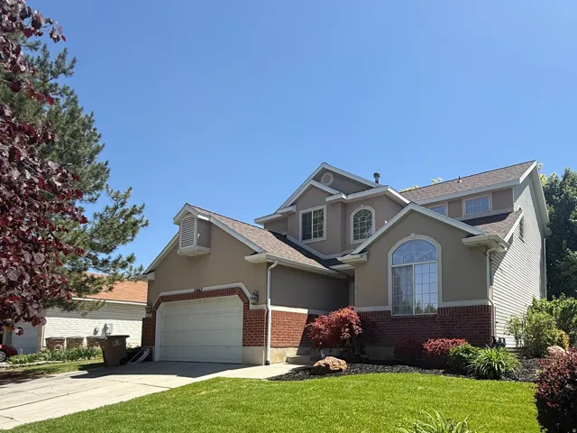 Two-story residence featuring a stucco and brick exterior, an attached two-car garage, and a gabled roofline