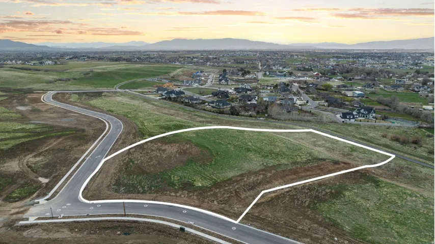 Expansive lot with a grassed area and partial road frontage, framed by a distant mountain range