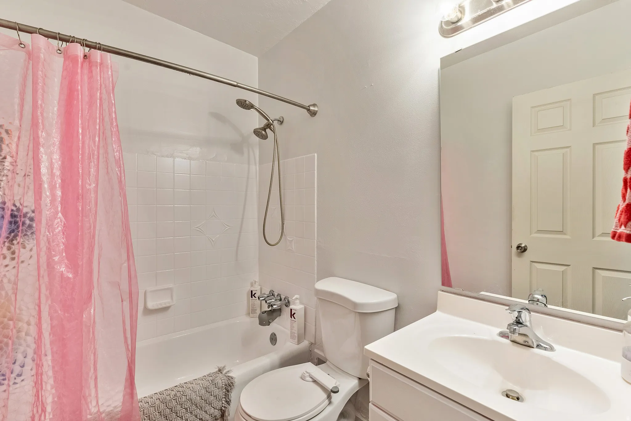 Bathroom featuring a white vanity with integrated sink, chrome faucet, and a large mirror