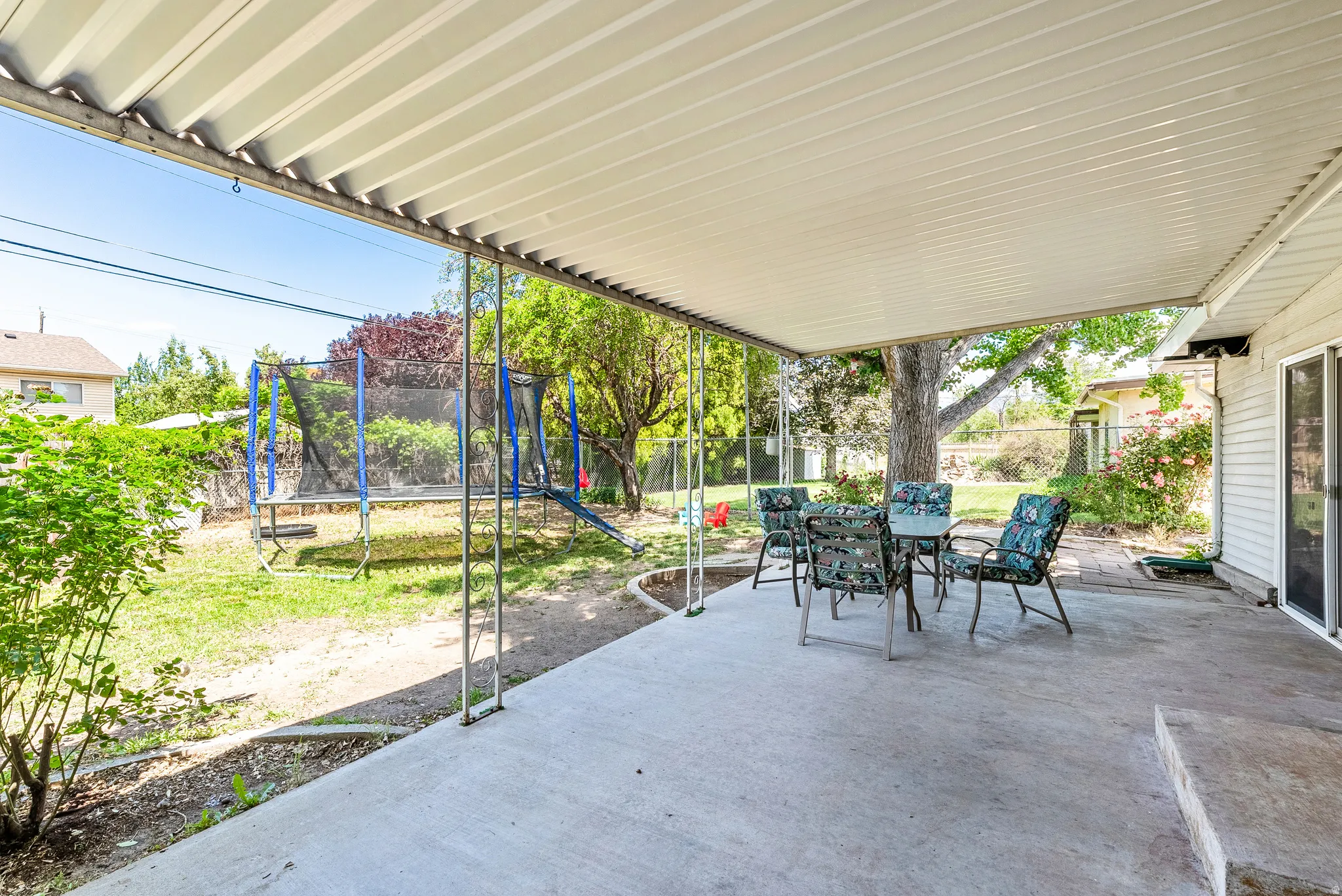 Expansive covered patio featuring a concrete slab, white corrugated roofing, and direct yard access