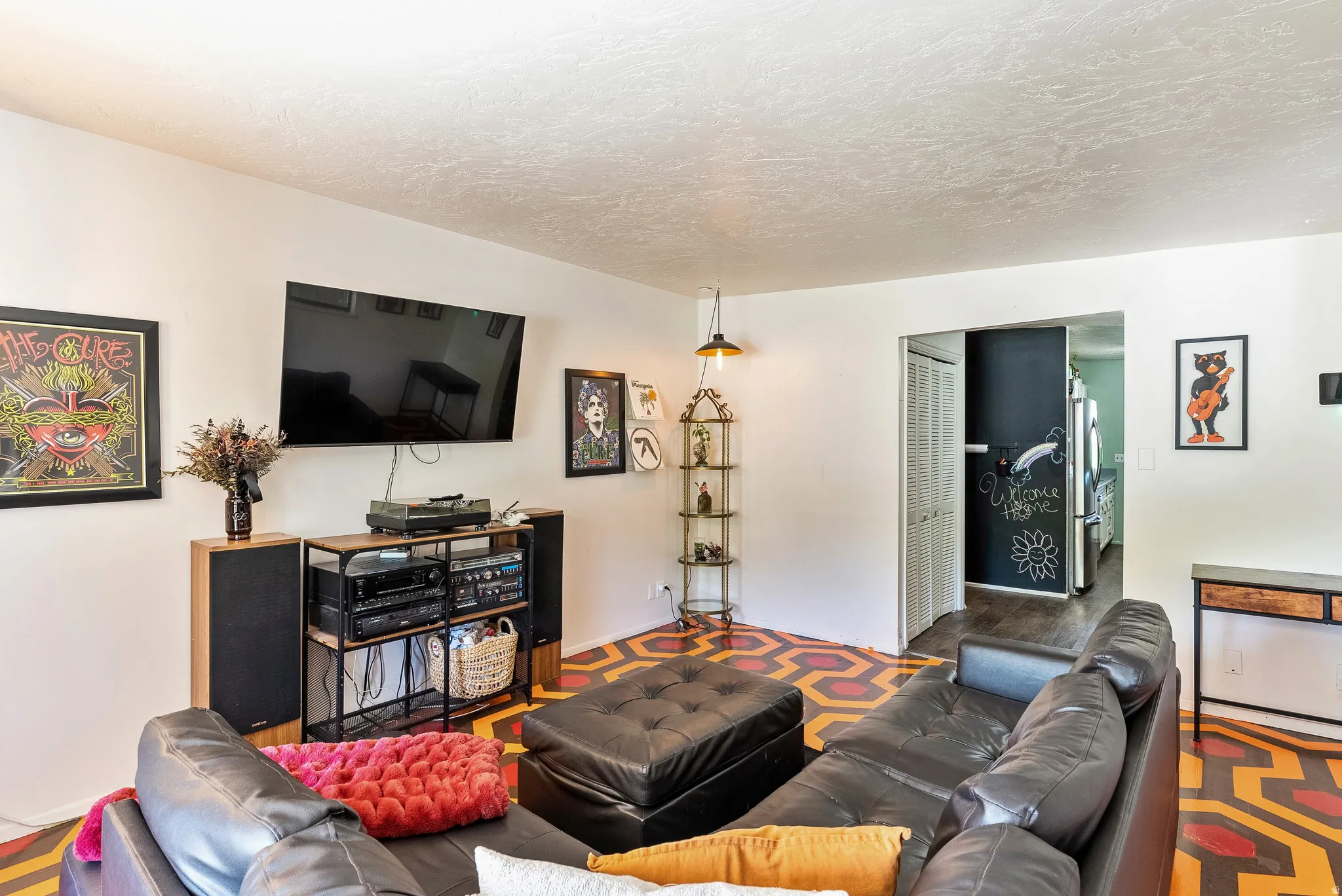 Living area featuring unique geometric patterned flooring, white walls, and an open doorway leading to an additional space