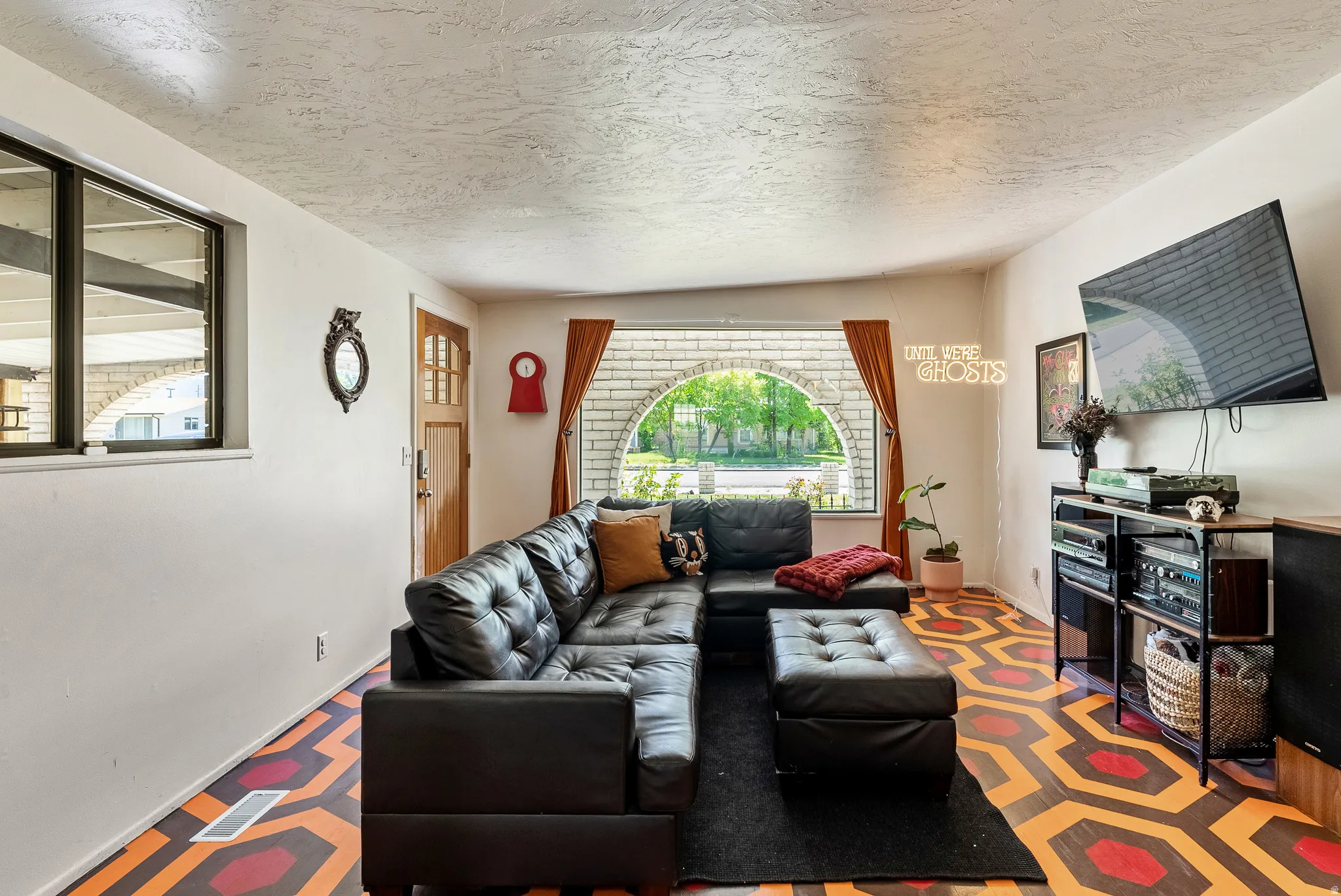 Living space featuring a distinctive patterned floor, a prominent arched window, and a paneled entry door