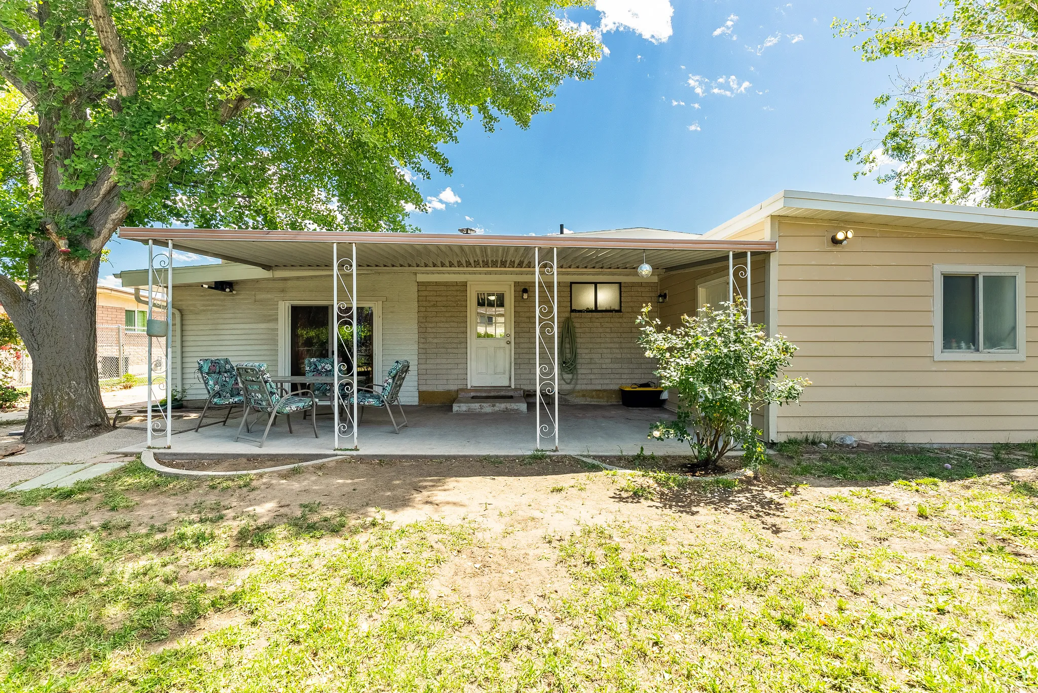 Rear exterior featuring a covered patio with decorative metal support columns and a concrete slab