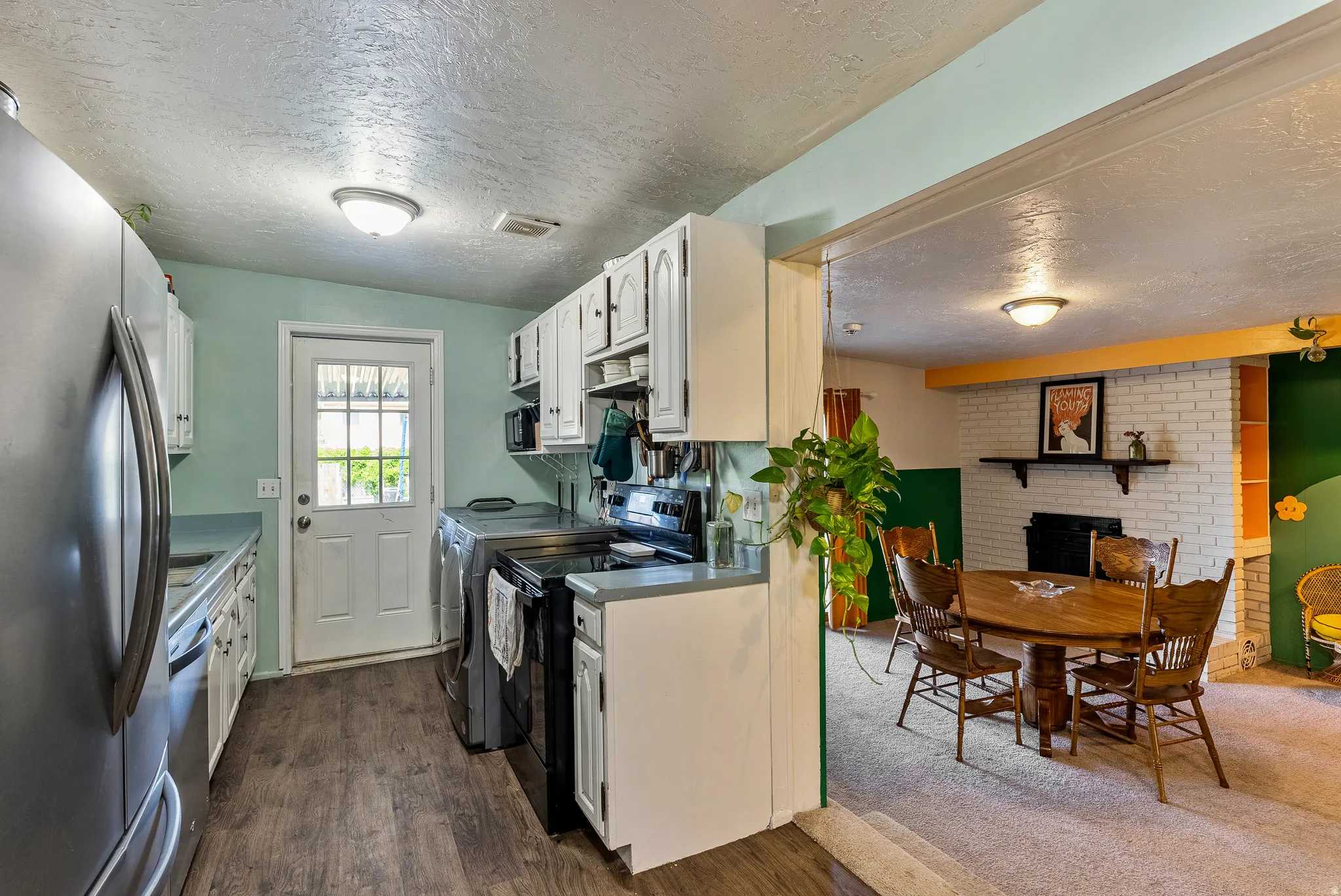 Kitchen featuring wood-finish flooring, white cabinetry, and stainless steel appliances