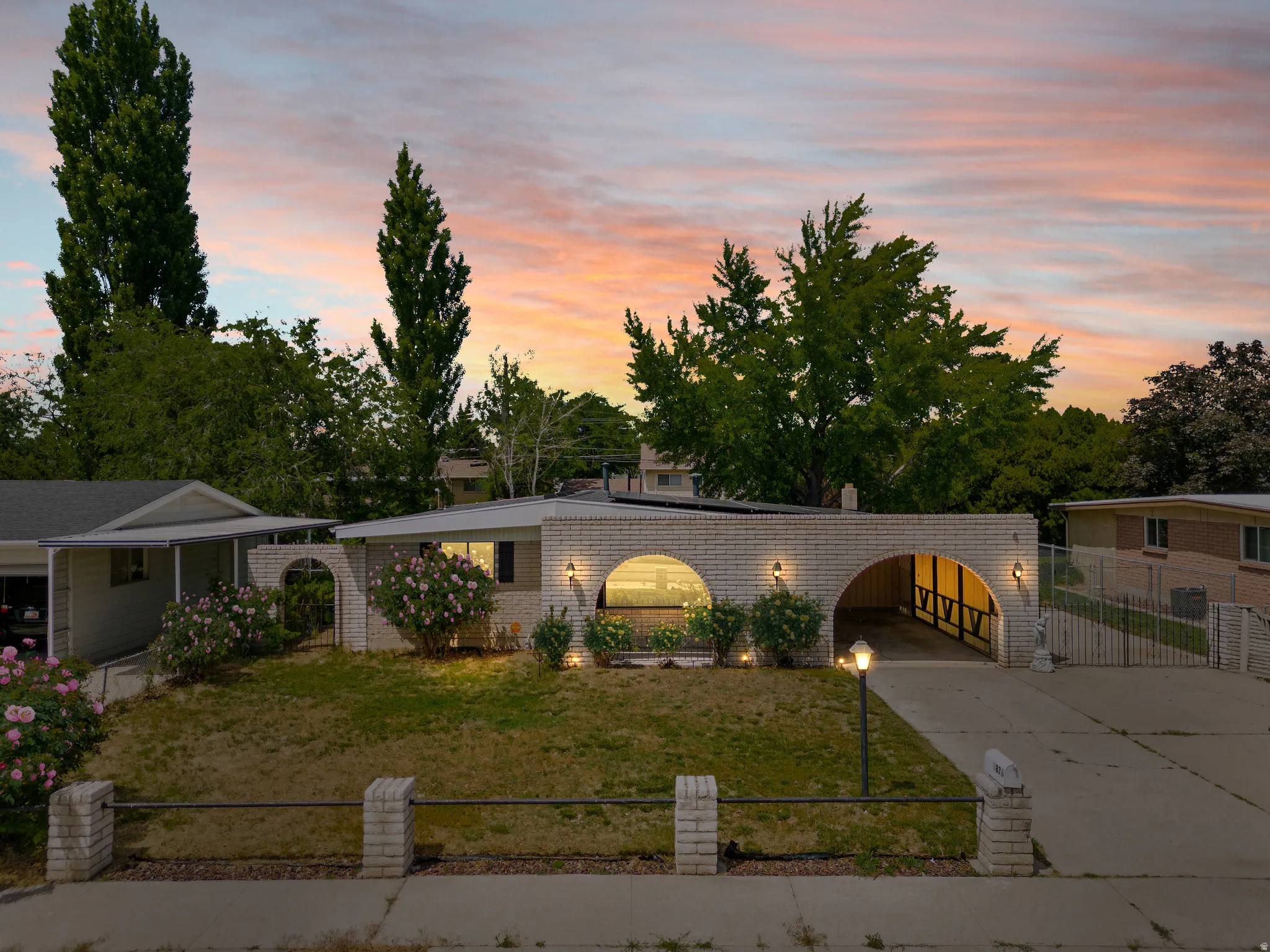 White brick exterior featuring arched carports and entryways