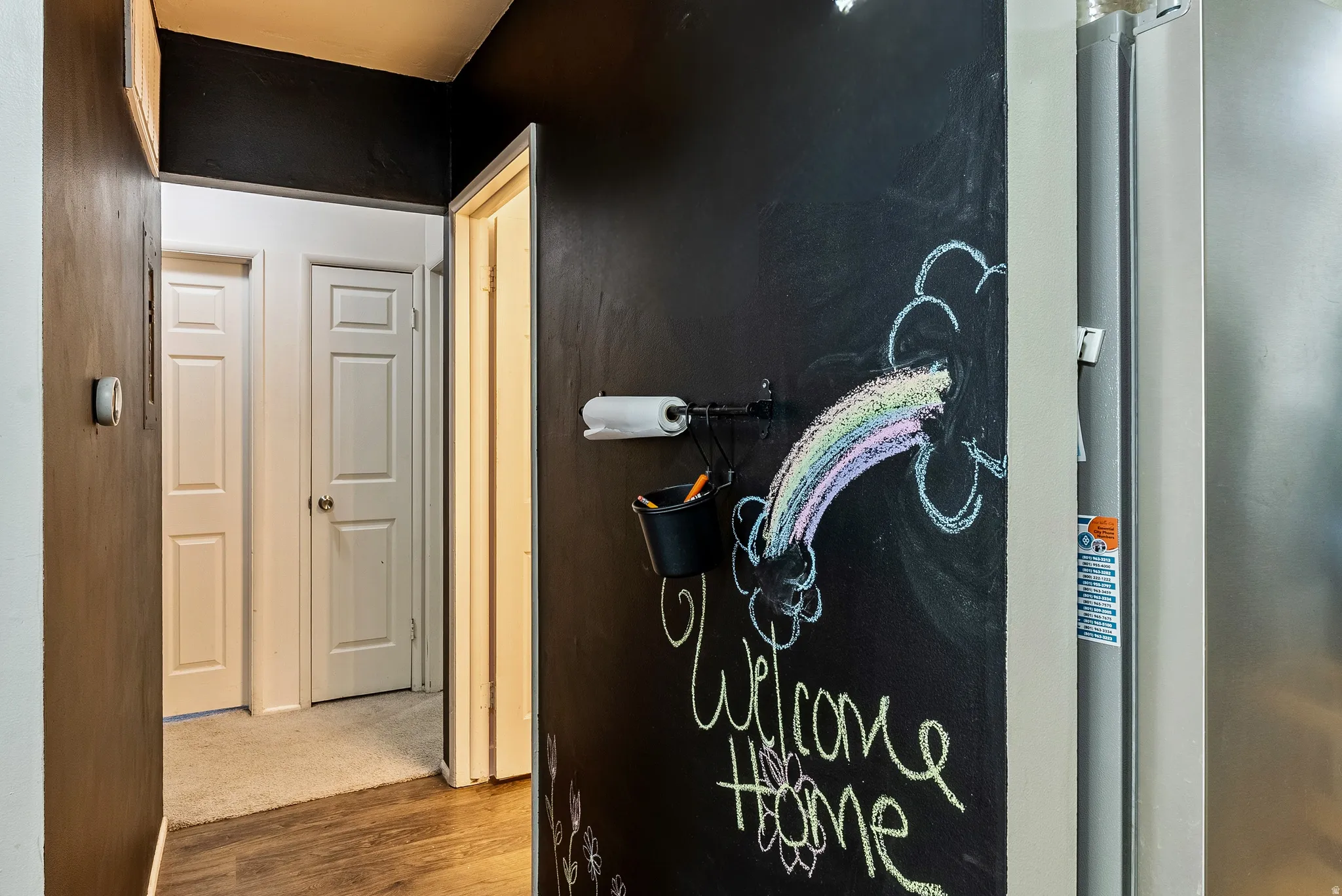 Chalkboard wall feature with a wall-mounted paper towel holder and storage bucket