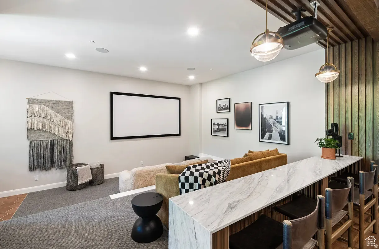 Dedicated media room featuring a large projection screen, recessed lighting, and integrated ceiling speakers