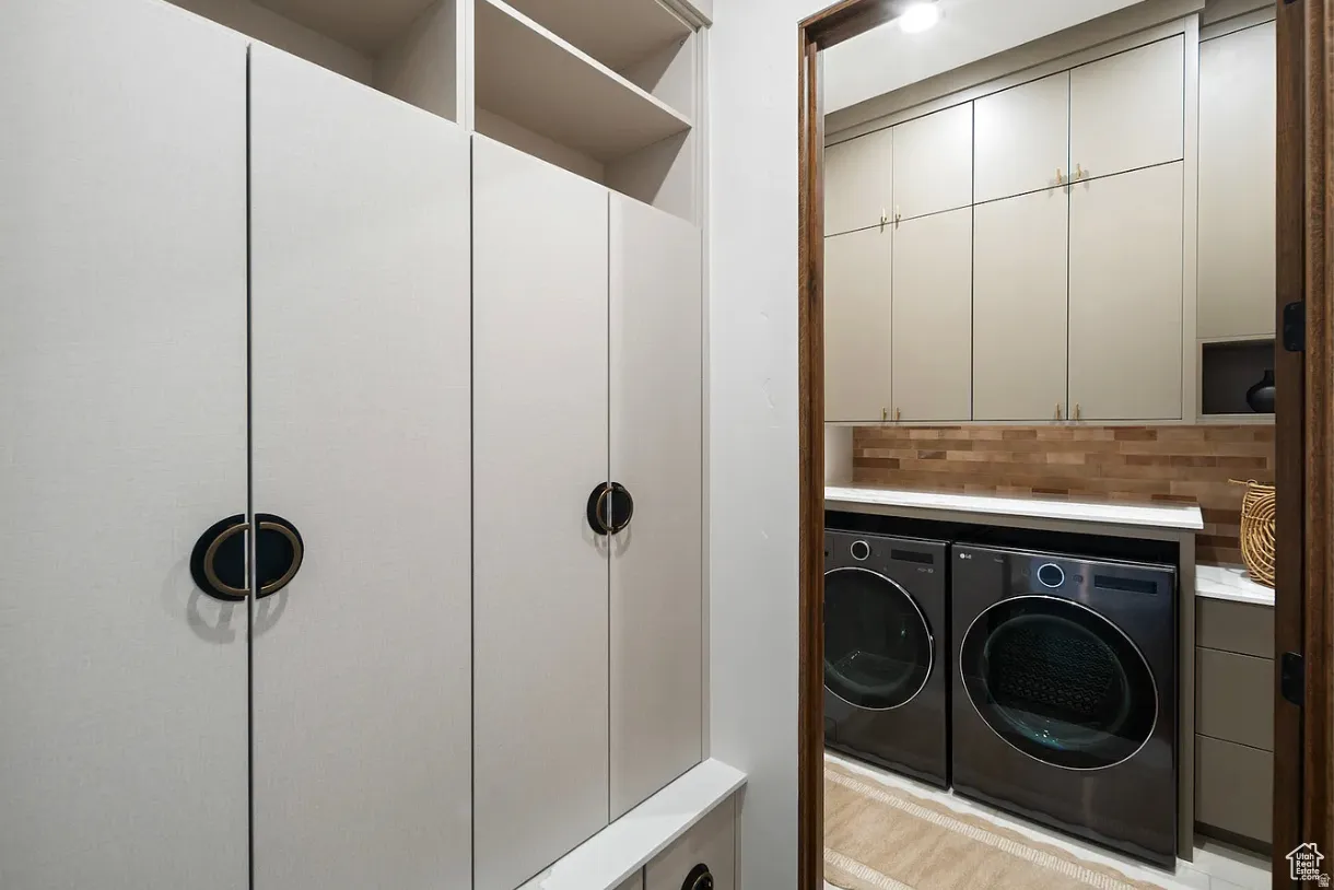 Dedicated laundry area with warm wood-tone backsplash, contrasting cabinetry, integrated countertop, and overhead shelving
