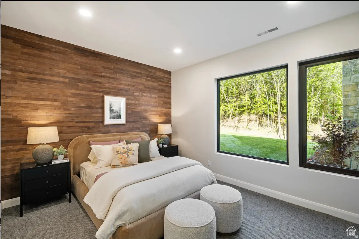 Accent wall featuring horizontal wood planks, recessed ceiling lighting, two large rectangular windows, and gray carpet flooring