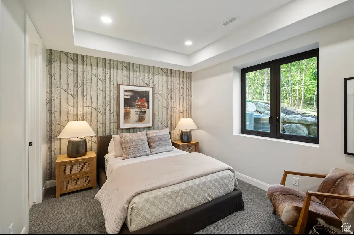 Recessed ceiling lighting illuminates a room featuring a tree-patterned accent wall