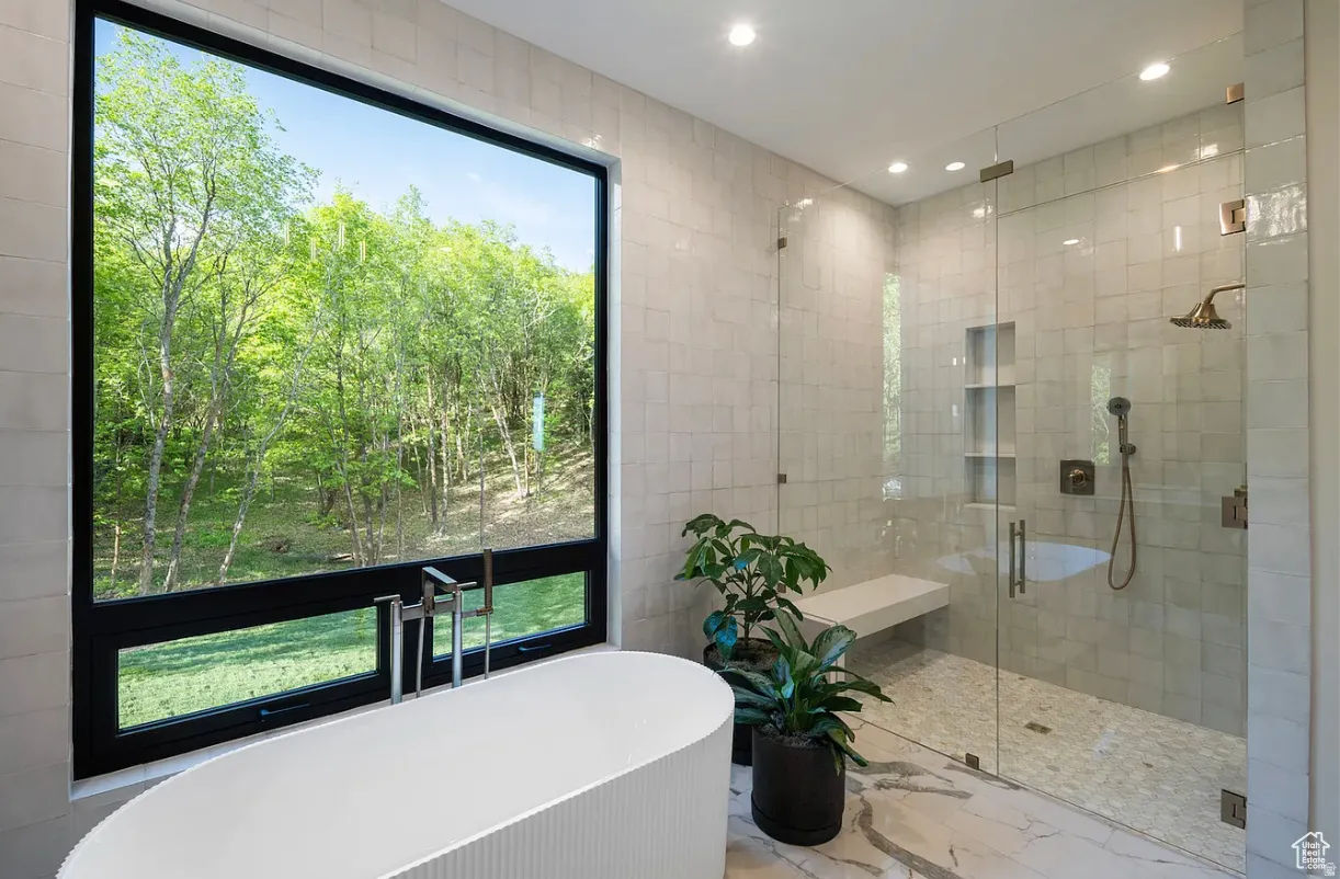 Freestanding soaking tub with floor-mounted fixtures, set against a large picture window