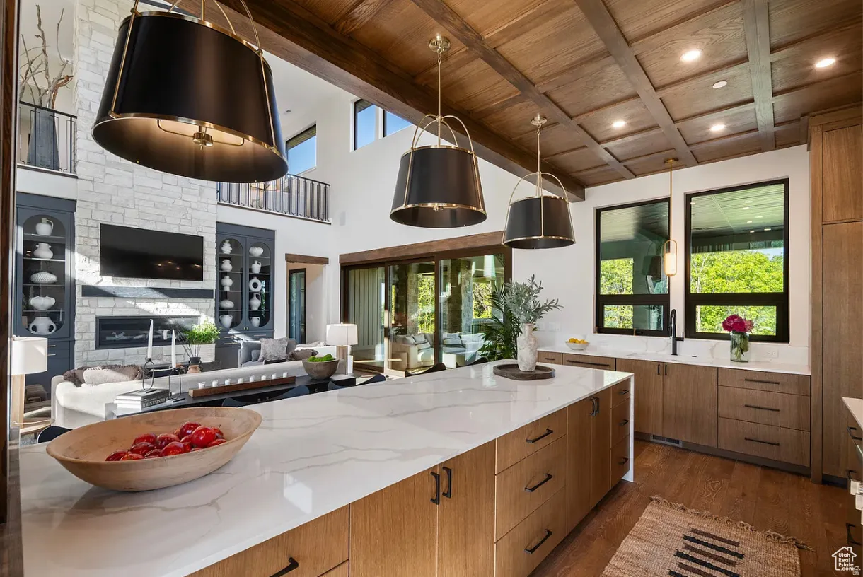 Spacious kitchen featuring a large island with a light-toned countertop, wood-finish cabinetry, and wood-finish flooring