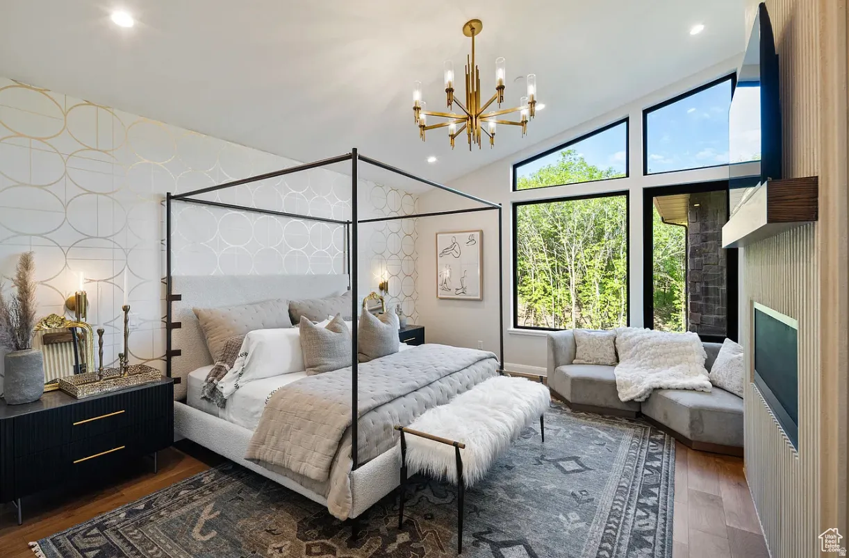 Vaulted ceilings with an angular window wall, a modern chandelier, and wood-finish flooring