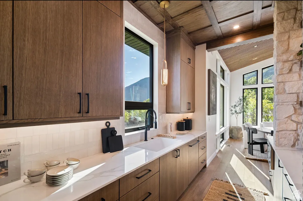 Modern kitchen featuring wood-finish cabinetry, white subway tile backsplash, and a large window