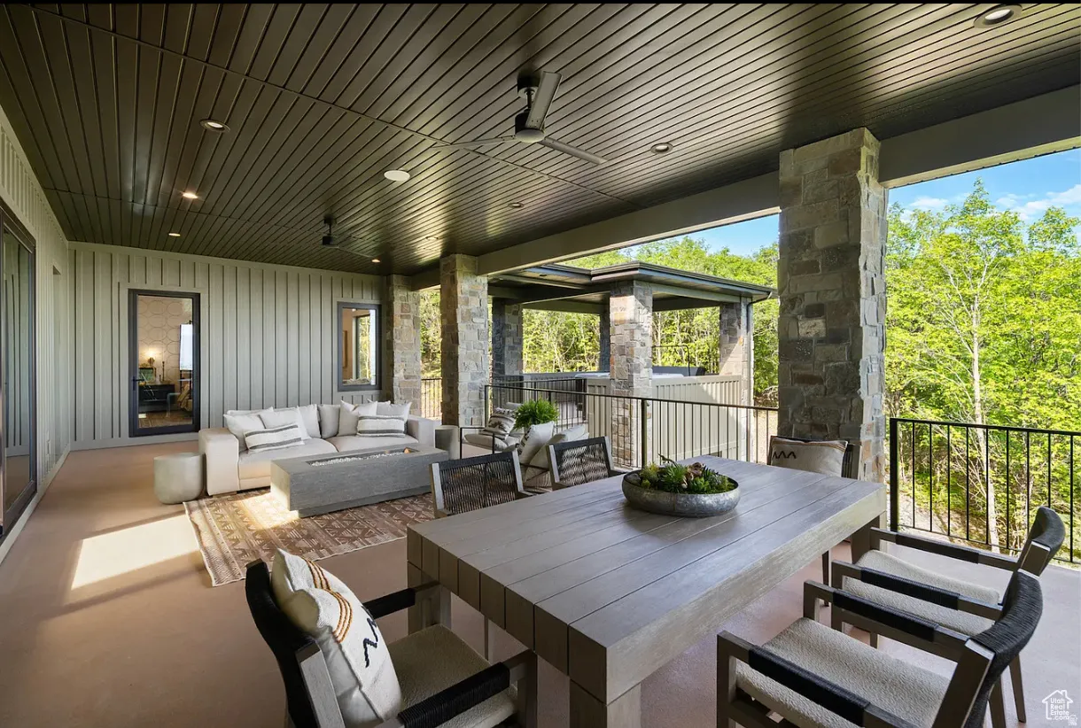 Expansive covered patio featuring a slatted ceiling, recessed lighting, and stone support columns