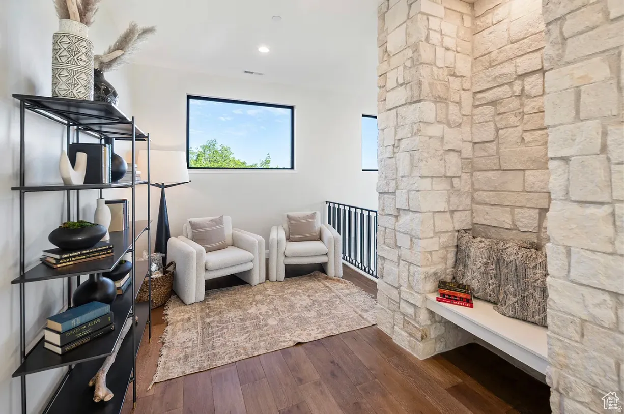 Upper-level landing featuring wood-finish flooring, a stone accent wall with a built-in bench, and black frame windows