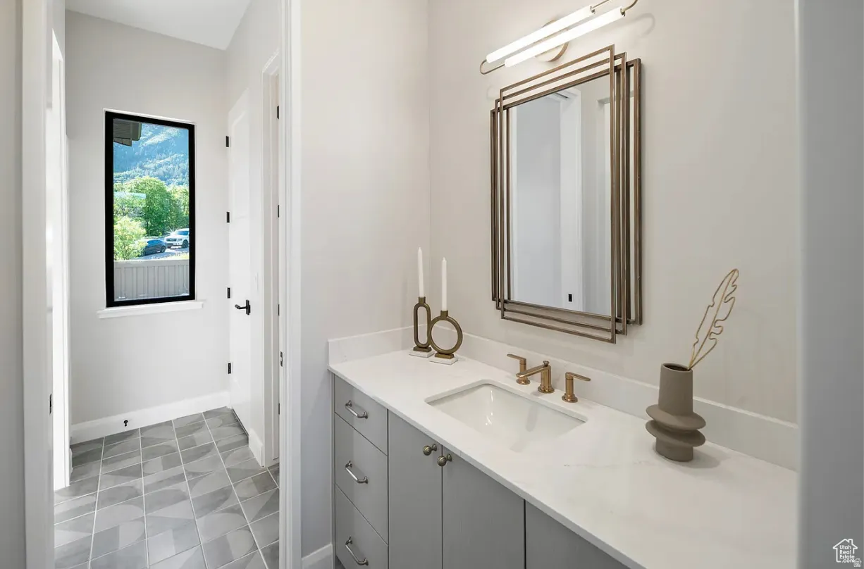 Vanity featuring an integrated rectangular sink with bronze-finish faucet, white countertop, and gray cabinetry