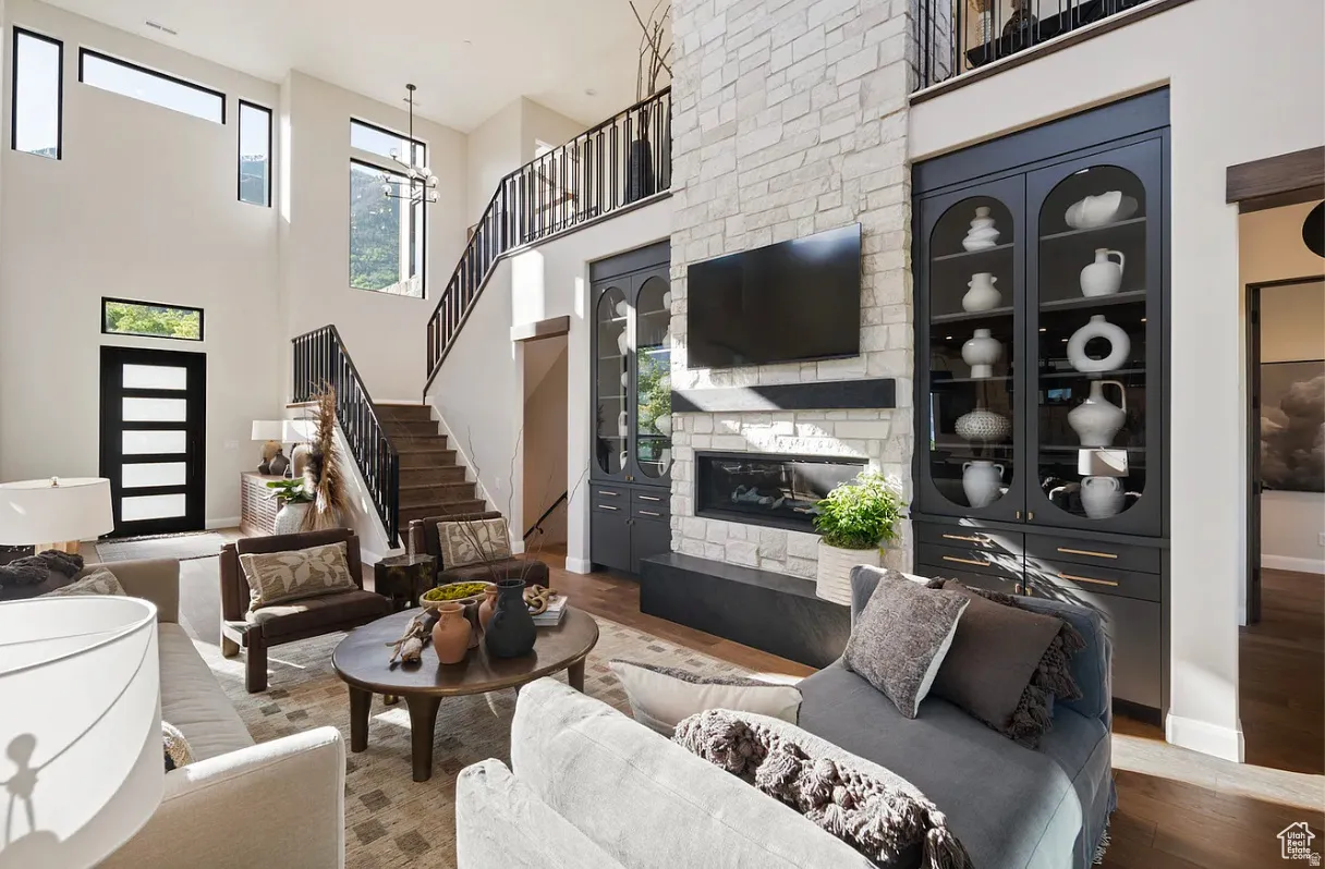 Double-height living space featuring a stone-clad fireplace, integrated media console, and built-in display cabinetry