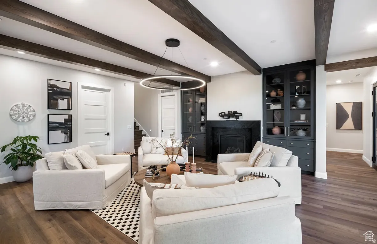 Living area featuring wood-finish flooring, exposed ceiling beams, and a modern circular pendant light