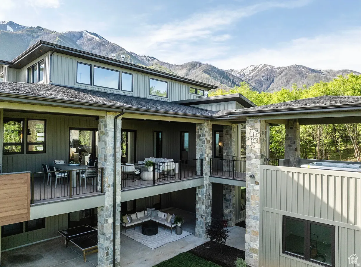 Multi-level exterior featuring stone accents, multiple covered balconies, a ground-level patio, and a covered hot tub