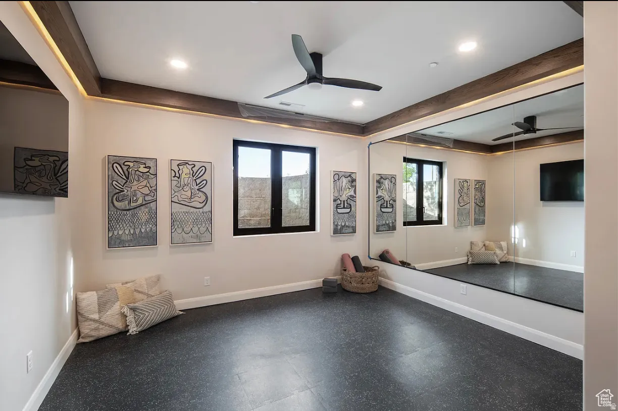 Dedicated fitness space featuring resilient flooring, a full-wall mirror, two black-framed windows, recessed lighting, and a ceiling fan