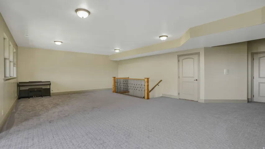 Spacious room featuring patterned gray carpeting, light beige walls, and multiple flush-mount ceiling lights