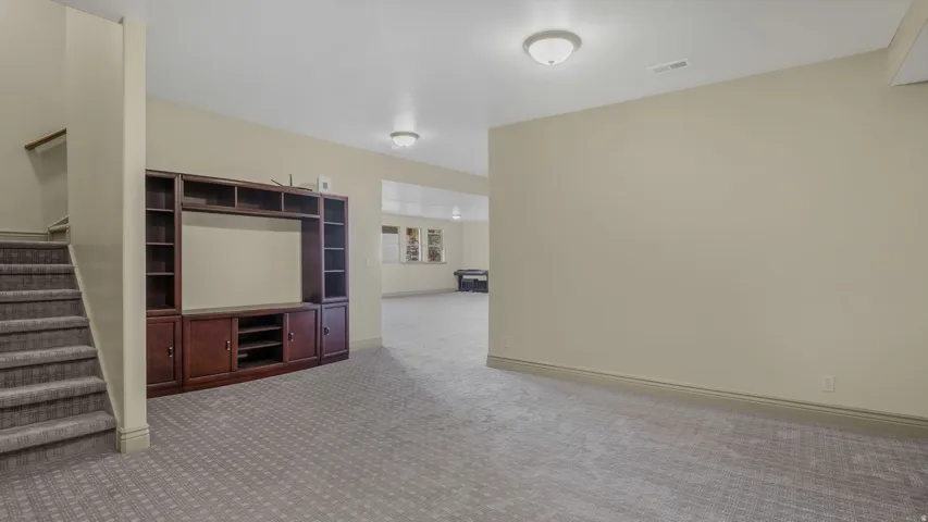 Spacious lower-level area featuring neutral-toned walls, patterned carpeting, and recessed lighting fixtures