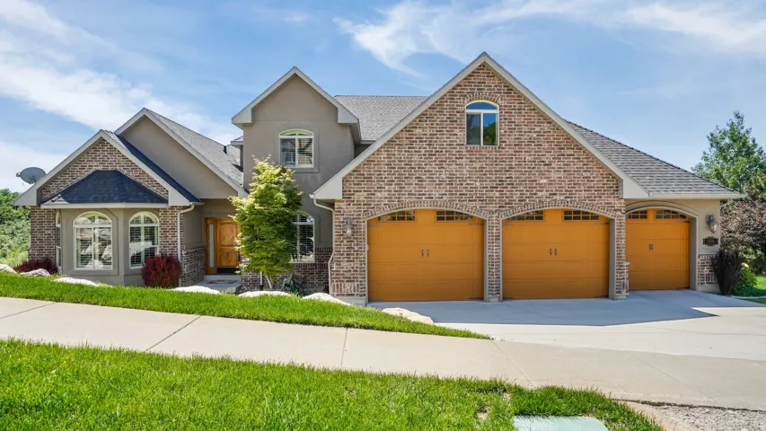 Stucco and brick facade with arched entryway over the three-car garage