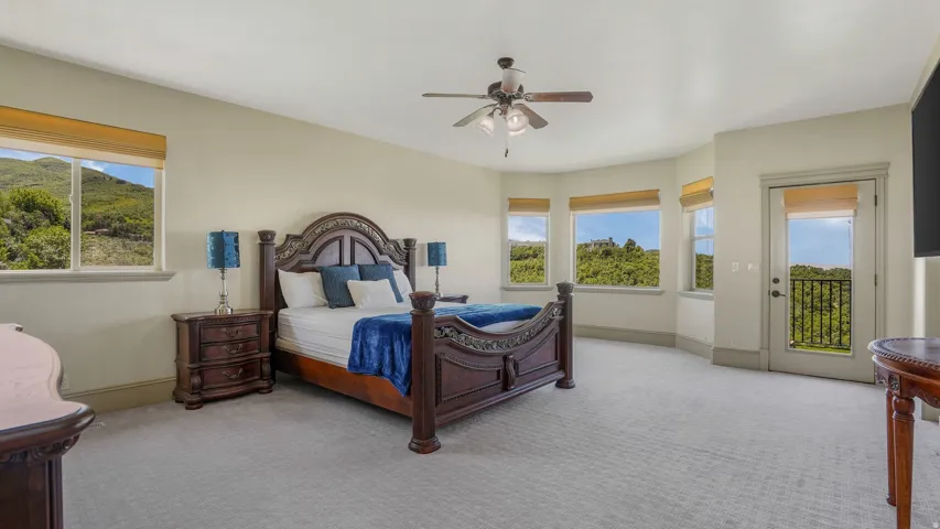 Spacious room featuring light-colored walls, patterned carpeting, and a ceiling fan