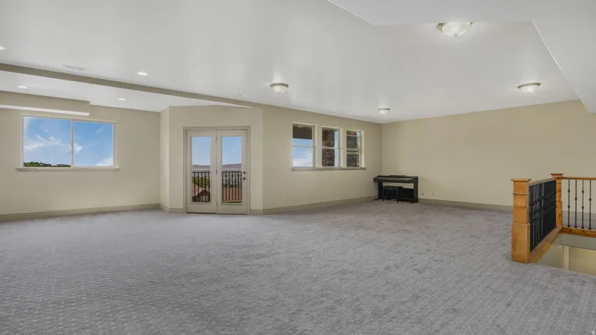 Spacious room featuring patterned gray carpeting, light-toned walls, and recessed lighting
