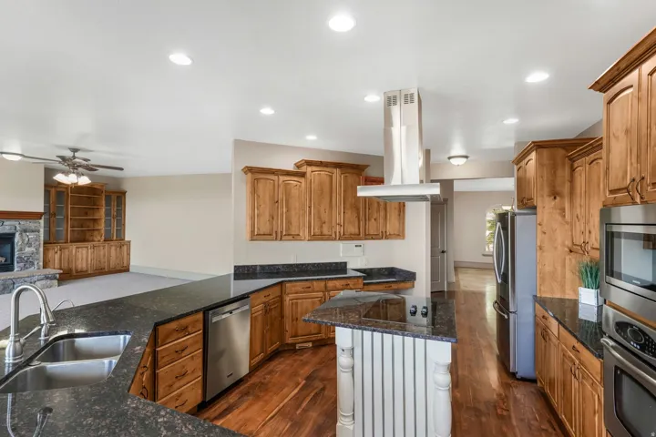 Kitchen featuring wood-finish flooring, dark granite countertops, and stainless steel appliances
